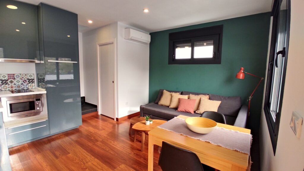 Salón con pared verde, sofá cama y cocina del dúplex de 1 dormitorio en Los Gata Gata, Las Negras