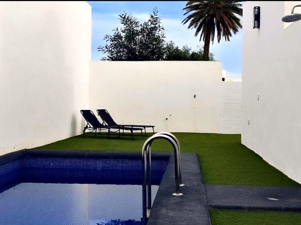 Piscina compartida con tumbonas y césped